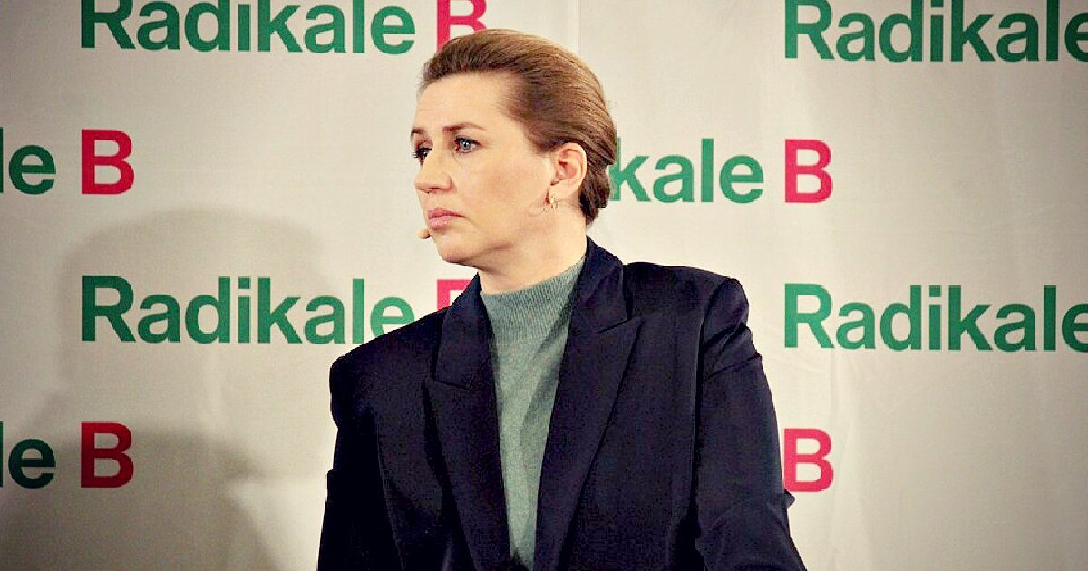 A woman in a dark blazer and green sweater speaks at a podium with Radikale B branding in the background.
