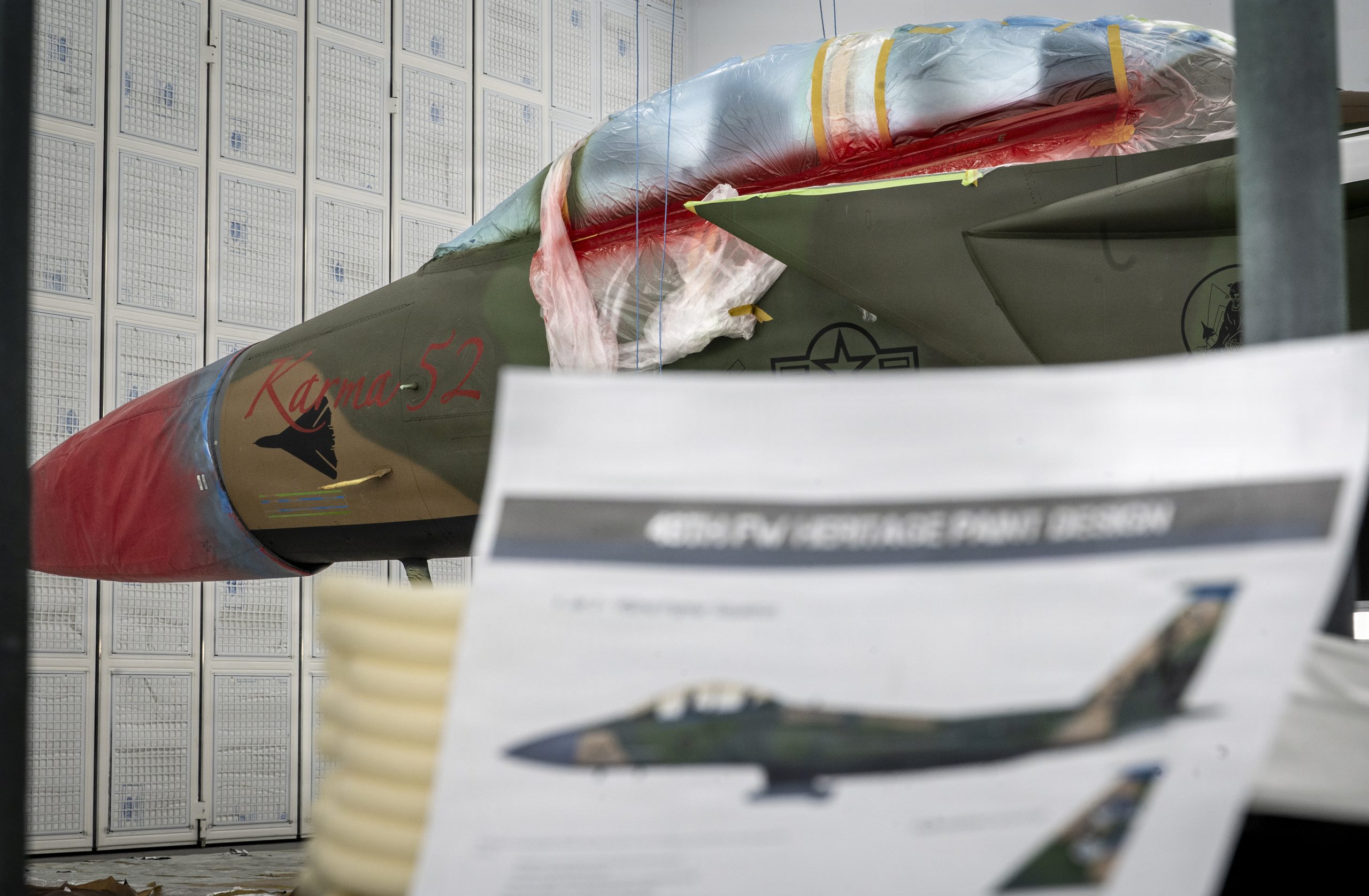 A U.S. Air Force F-15E Strike Eagle aircraft assigned to the 494th Fighter Generation Squadron sits behind a heritage design mock-up at RAF Lakenheath, England, March 18, 2026. During Operation El Dorado Canyon, an F-111F Aardvark “Karma 52” aircraft, the captain and the weapons system officer went missing while flying over the Mediterranean Sea. The markings on the modern paint scheme pay tribute to the personnel and aircraft that were lost during the mission. (U.S. Air Force photo by Airman 1st Class Rilynn Jacobs)