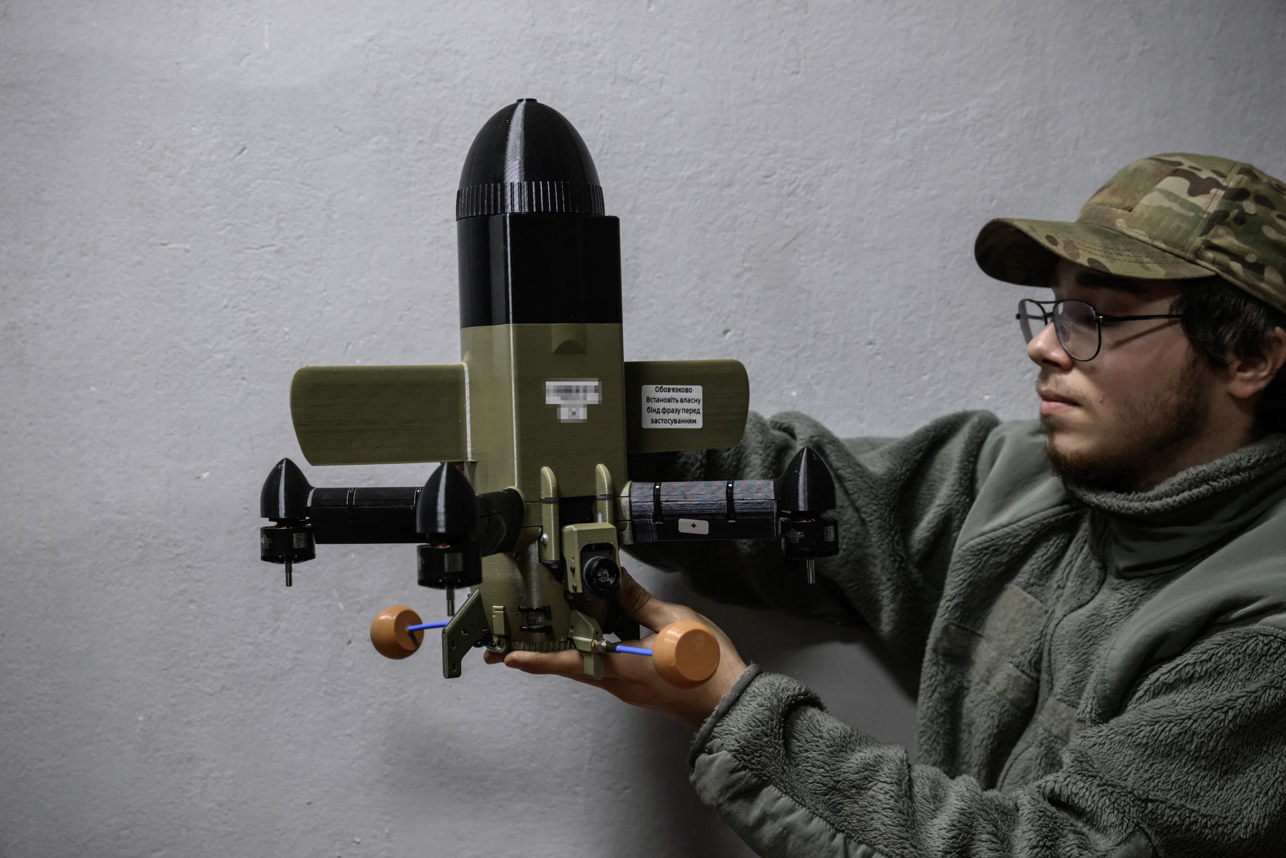 TOPSHOT - A member of the 3rd Army Corps Interception Squadron holds an interceptor drone used to protect against Russian drone attacks, at an undisclosed location near the front lines of eastern Uraine, on October 9, 2025. (Photo by Ed JONES / AFP via Getty Images)