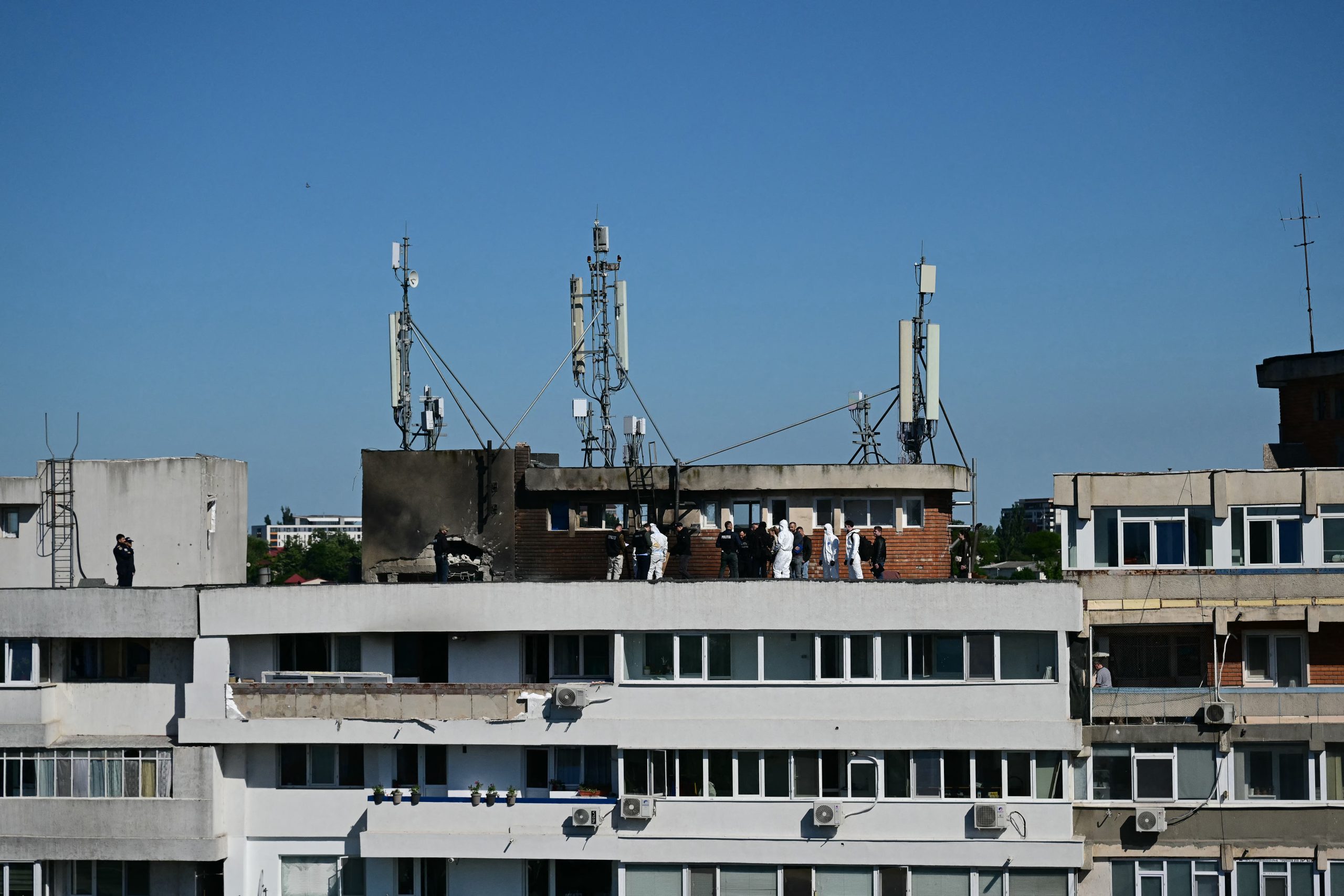 Police and forensic investigators stand on the rooftop as they examine the location of impact (L) over a damaged apartment after a Russian drone struck an apartment building in Galati, eastern Romania. A Russian drone wounded two people as it struck an apartment building in NATO-member Romania, its defence ministry said on May 29, 2026, the latest spillover from the four-year war into neighbouring states. (Photo by Daniel MIHAILESCU / AFP via Getty Images)