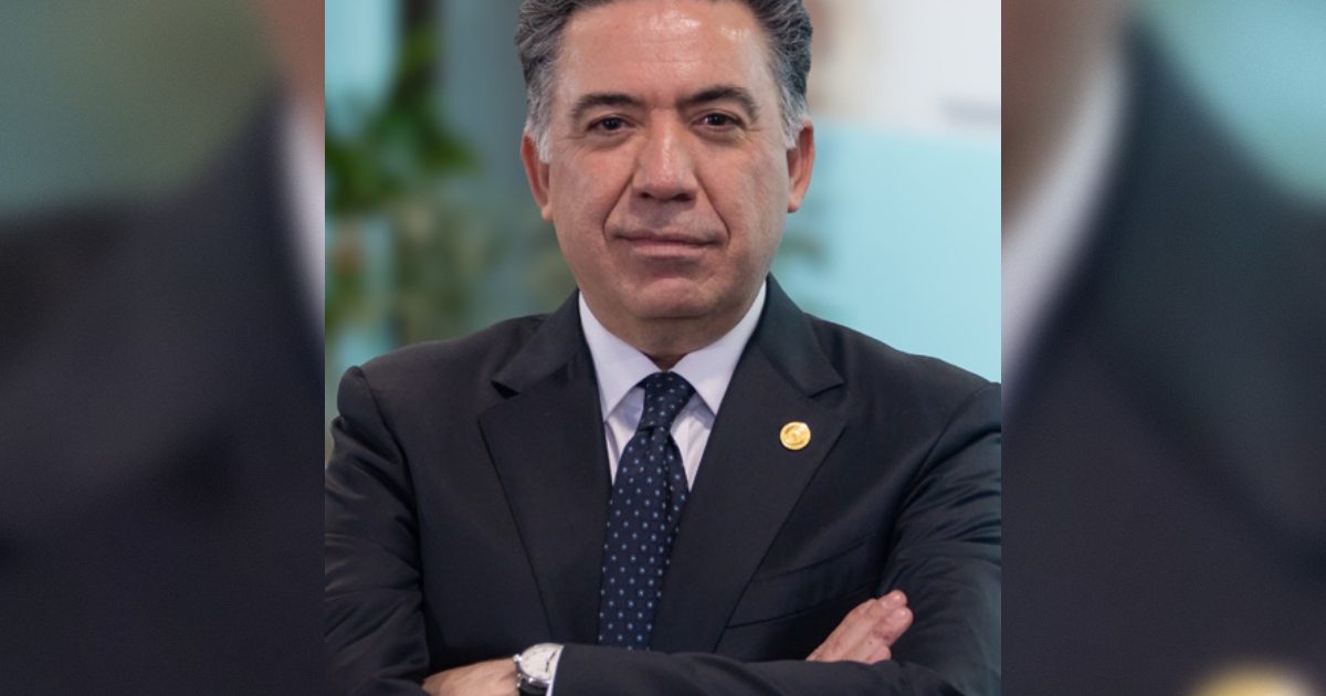 Business professional in a suit with arms crossed, showcasing confidence and leadership in a modern office environment.