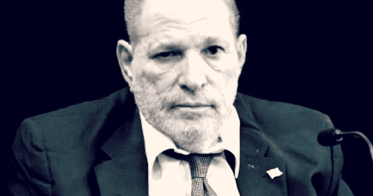 Harvey Weinstein appearing serious during a public hearing, wearing a suit and tie with a somber expression against a dark background.