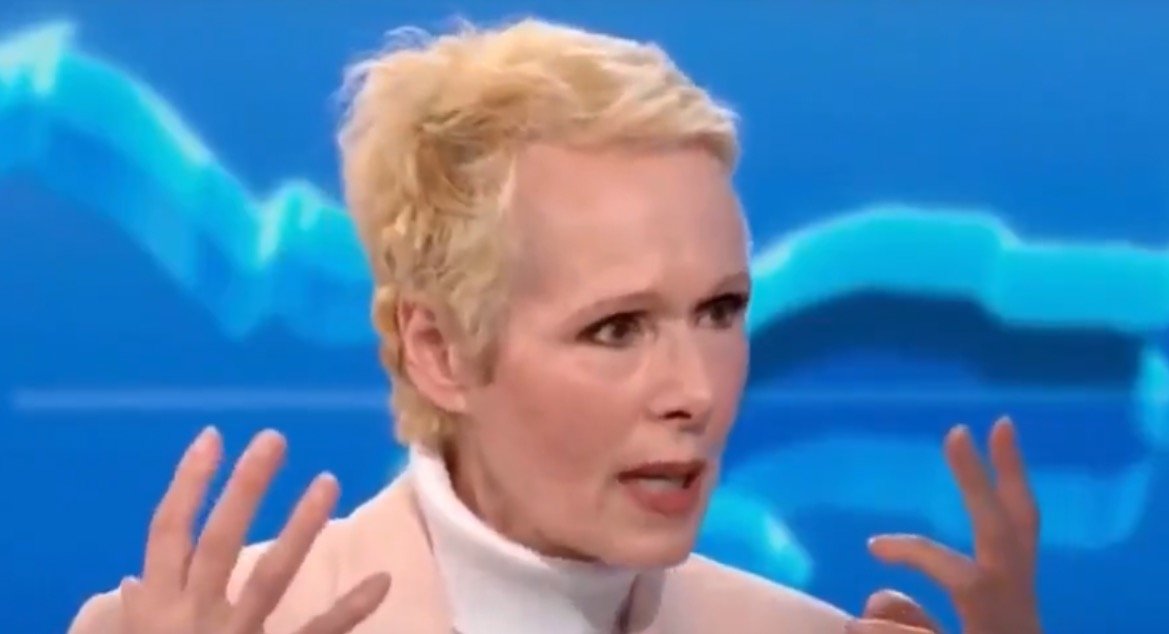 A woman with short blonde hair passionately discusses a topic on a television show, with graphs visible in the background.
