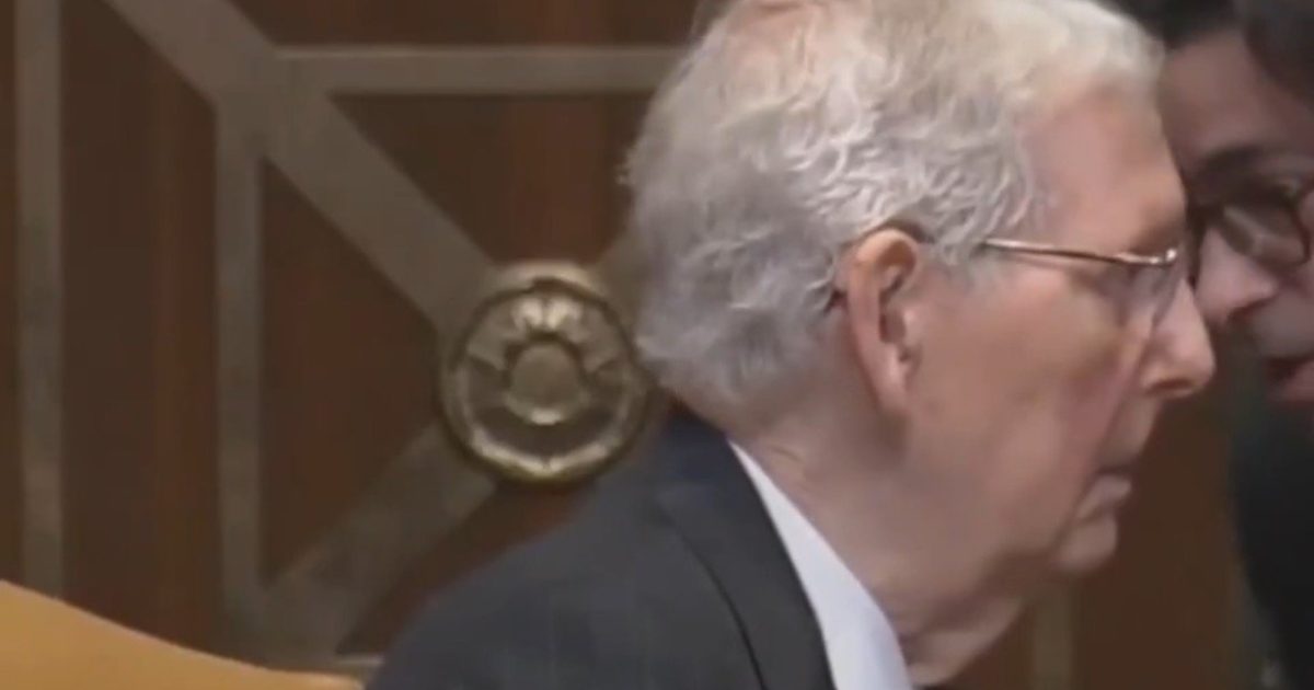 Close-up of two men engaged in conversation during a Senate hearing, highlighting the serious atmosphere and focus on political discussion.