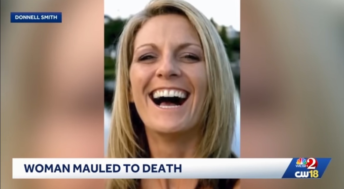 Smiling woman with long blonde hair, captured in a joyful moment, against a blurred outdoor background.
