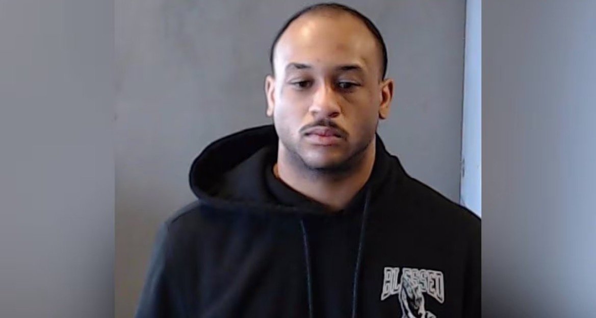 Mugshot of a man wearing a black hoodie, looking directly at the camera against a neutral background.
