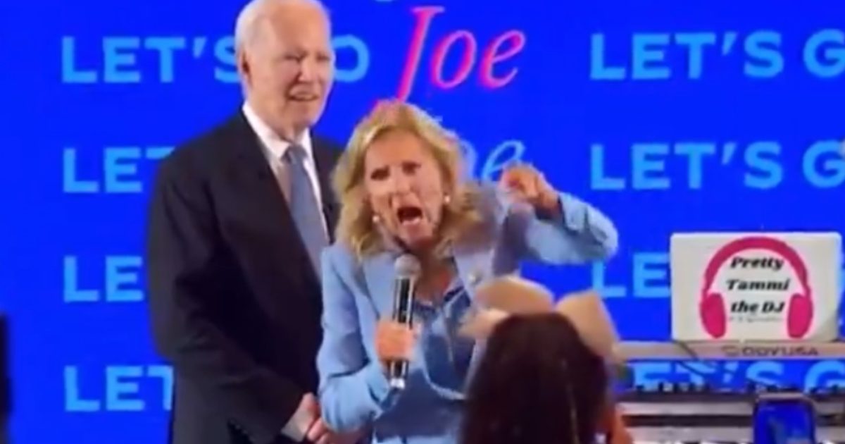 Jill Biden passionately speaks at a campaign event with Joe Biden smiling in the background, promoting enthusiasm among supporters.