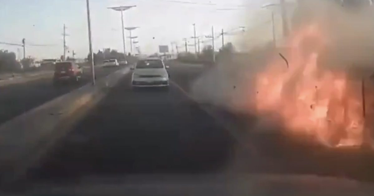 Traffic scene with a car driving past a roadside fire, highlighting a dangerous situation on the highway.