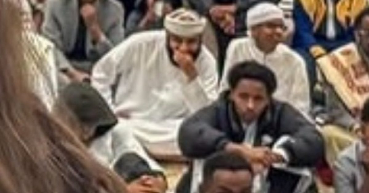 Audience engaged in a cultural event, featuring diverse individuals in traditional and modern attire, showcasing community interaction and participation.