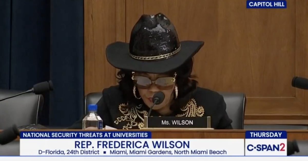Congresswoman Frederica Wilson participates in a hearing on national security threats at universities, wearing a distinctive black hat and glasses.