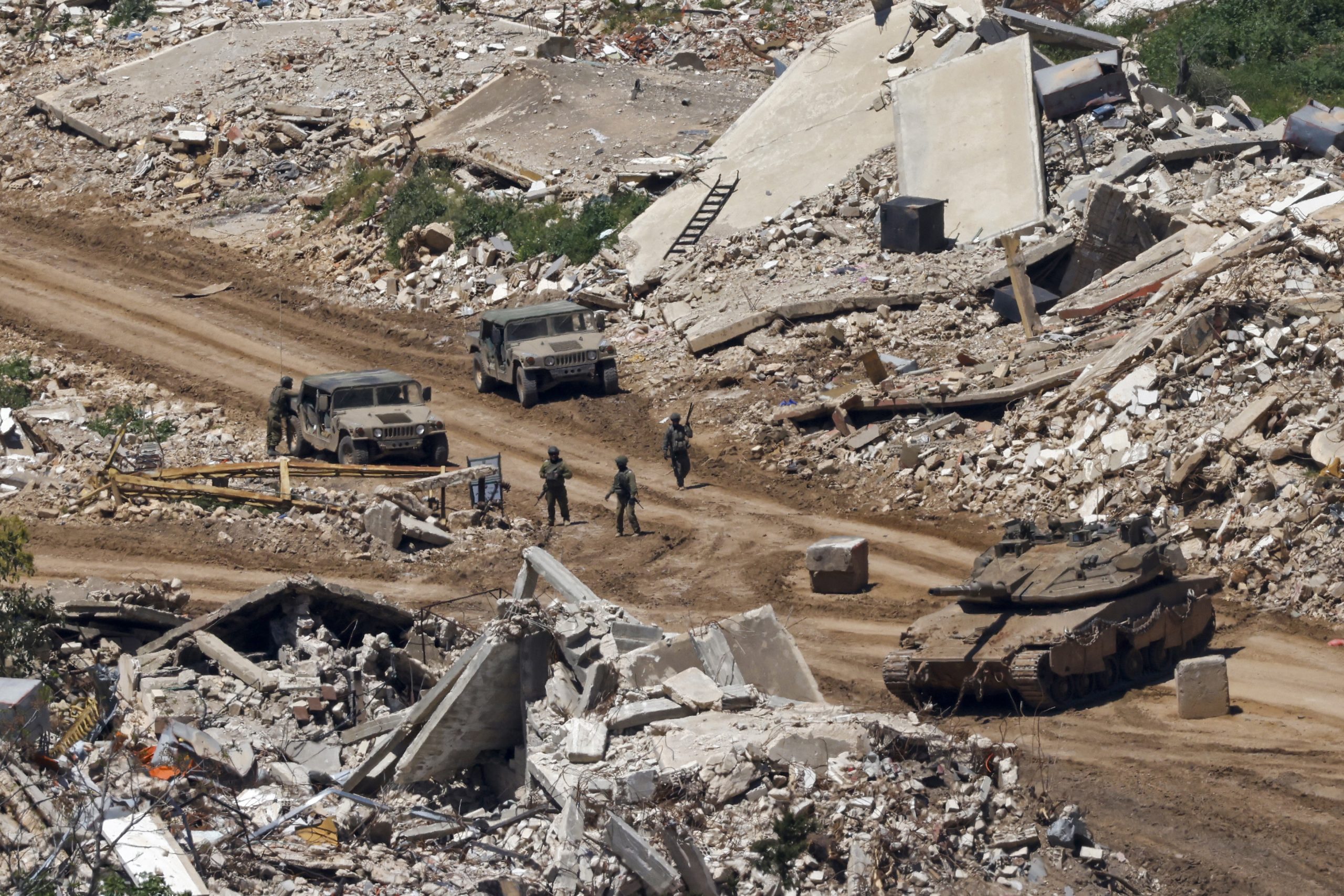 TOPSHOT - This photograph taken from the northern Israel shows Israeli tanks and military vehicles standing along the road between destroyed houses in southern Lebanon near the border with Israel, on April 29, 2026. Lebanon's army said on April 29 that one of its soldiers was among two people killed in an Israeli strike in the country's south, the latest deadly raid despite a ceasefire in the Israel-Hezbollah war. (Photo by Jalaa MAREY / AFP via Getty Images)