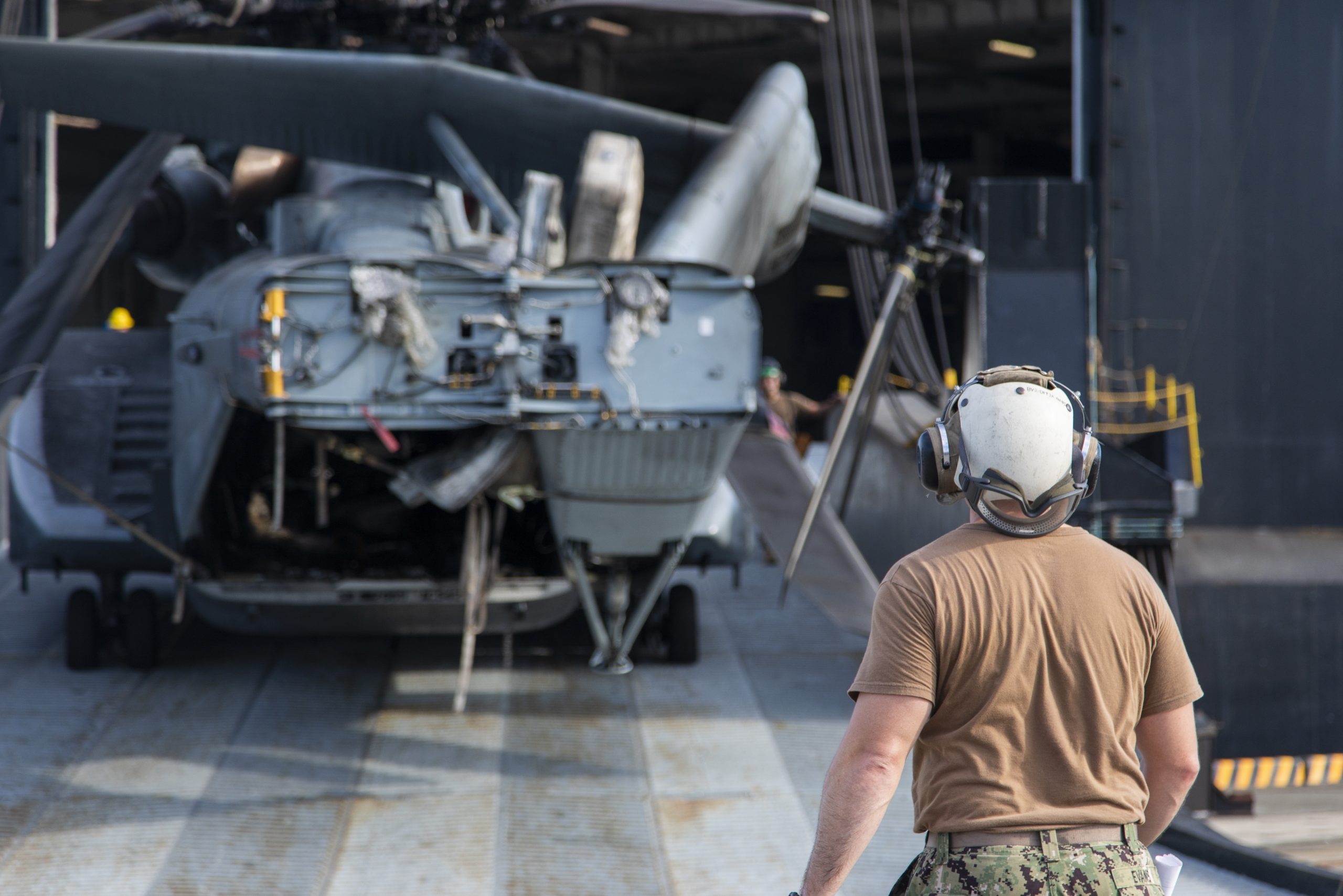 A U.S. Navy Sailor with Helicopter Mine Countermeasures Squadron 14 guides an MH-53 helicopter from a vehicle carrier ship at Marine Corps Air Station Iwakuni, Japan, Sept. 14, 2022. The Green Lake visited MCAS Iwakuni to offload an MH-53 Sea Dragon in support of Helicopter Mine Countermeasures Squadron 14 after completion of aircraft maintenance. MCAS Iwakuni is the only Marine Corps base with a collocated harbor and airfield, allowing aircraft to be rapidly transported, fixed, and redeployed. (U.S. Marine Corps photo by Cpl. Darien Wright)