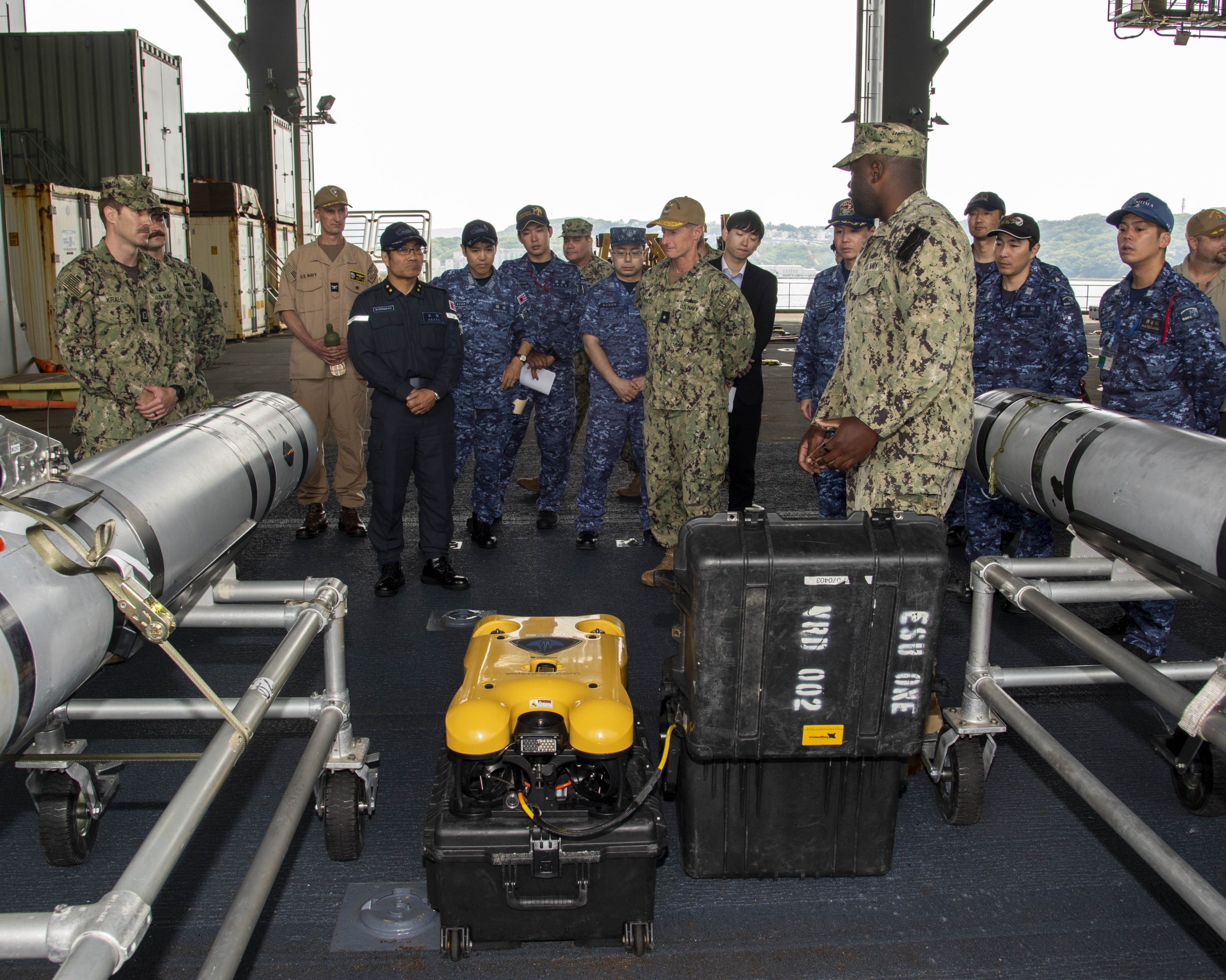 SASEBO, Japan (May 15, 2025) – A Sailor assigned to Explosive Ordnance Disposal Mobile Unit 5, describes the capabilities of the MK 18 Mod 2 Kingfish unmanned underwater vehicle and a remotely operated vehicle (ROV) to Japan Maritime Self-Defense Force Rear Adm. Yatsutaka Ebata, commander, Escort Flotilla 2, and Rear Adm. Tom Shultz, commander, Task Force (CTF) 76, during the Integrated Battle Problem 25.5 technology demonstration aboard the Lewis B. Puller-class Expeditionary Sea Base USS Miguel Keith (ESB 5), at Fleet Activities Sasebo, Japan, May 15, 2025. Exercises such as Integrated Battle Problem allow the Navy to demonstrate unmanned system operations in relevant experiment scenarios in order to meet service level objectives and operationalize unmanned systems and capabilities to maintain a secure and prosperous Indo-Pacific region. U.S. 7th Fleet, the U.S. Navy’s largest forward-deployed numbered fleet, routinely interacts and operates with allies and partners in preserving a free and open Indo-Pacific region. (U.S. Navy photo by Mass Communication Specialist 1st Class W. Chase Stephens)