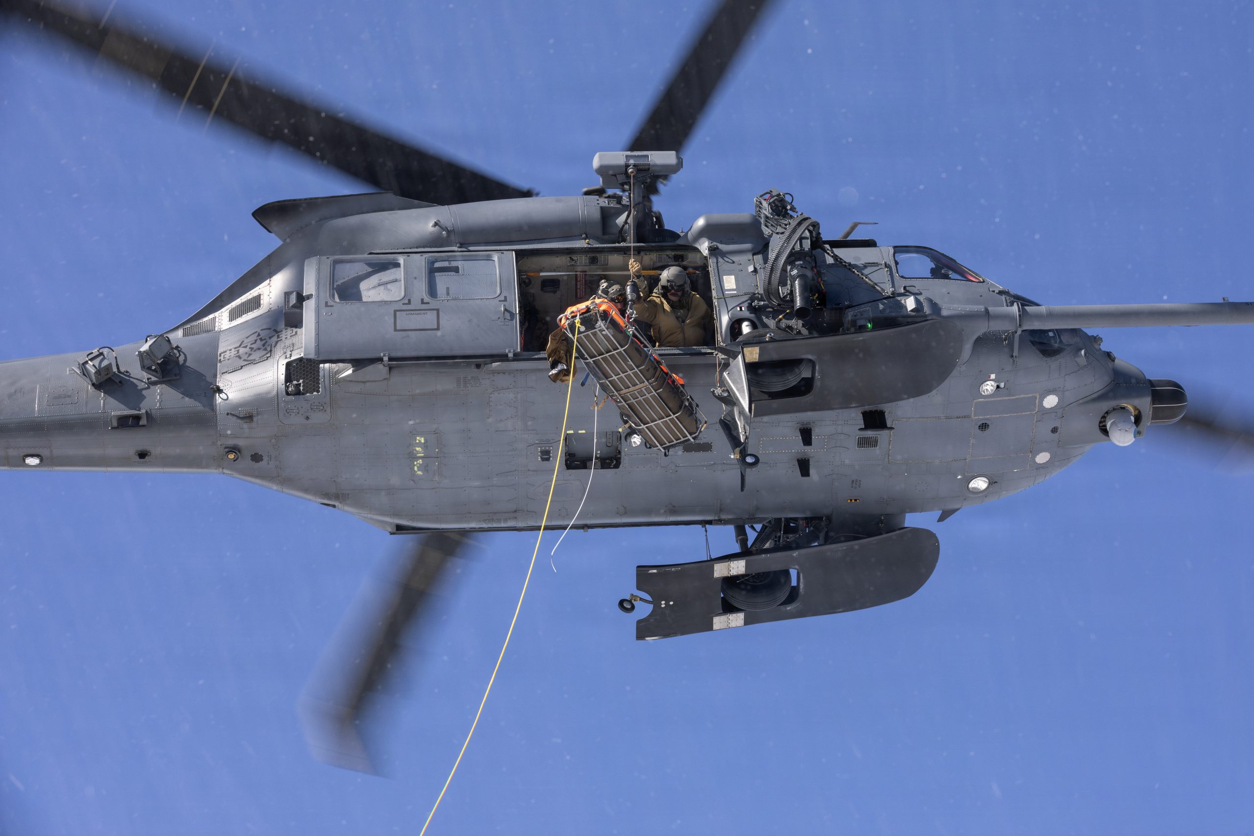U.S. Air Force HH-60W Jolly Green II helicopter aircrew assigned to the 210th Rescue Squadron, 176th Wing, Alaska Air National Guard, hoist a simulated downed pilot during a full mission profile training exercise at Malemute Drop Zone, Joint Base Elmendorf-Richardson, Alaska, March 31, 2026. The training included search and rescue, high-altitude parachute drops, emergency medical response, personnel recovery, and rescue hoist. Participants included HH-60W Jolly Green II aircrew of the 210th RQS, HC-130J Combat King II aircrew of the 211th RQS, and pararescuemen, and combat rescue officers of the 212th RQS. The three squadrons compose the 176th Wing’s Rescue Triad and are among the busiest search and rescue units in the Department of War. (Alaska National Guard photo by Alejandro Peña)
