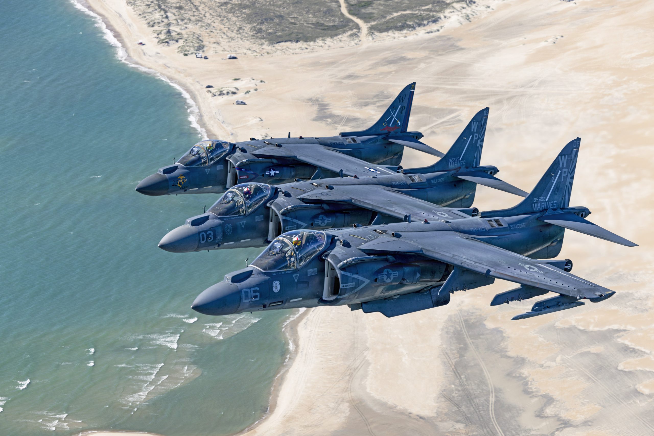 U.S. Marine Corps AV-8B Harrier II aircraft with Marine Attack Squadron (VMA) 223, Marine Aircraft Group 14, 2nd Marine Aircraft Wing, fly over the coast of North Carolina, May 15, 2026. The “sundown” of the AV-8B Harrier II, an iconic aircraft that has supported joint and Marine Corps operations for over 40 years, also represents the dawn of a new era; it paves the way for 2nd MAW’s full transition to the F-35B and C Lightning II. (U.S. Marine Corps photo by Lance Cpl. Perri Wood)