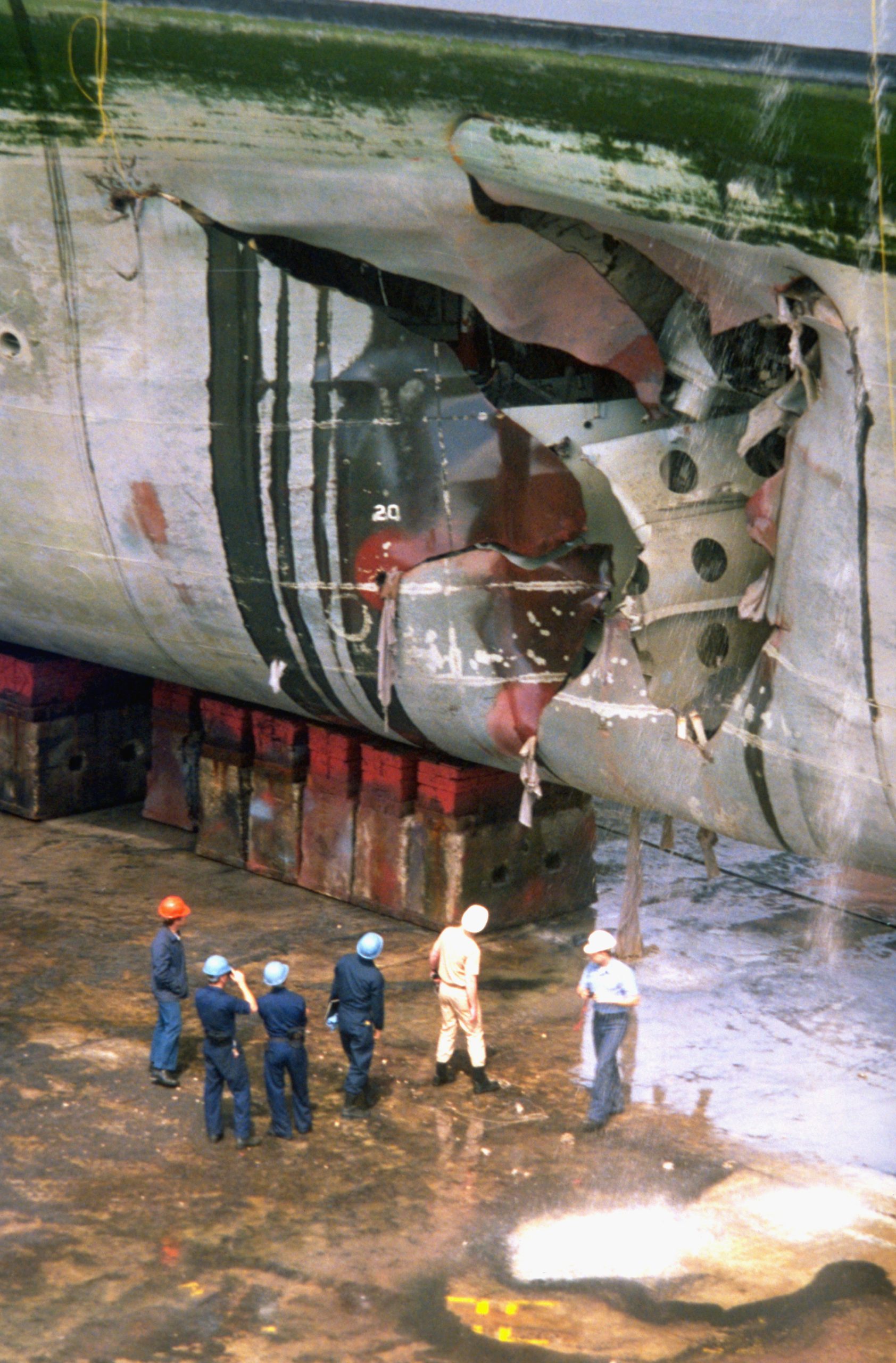 The amphibious assault ship USS Tripoli (LPH-10) lies in dry dock for repairs to a hole in its starboard bow caused by an Iraqi mine. The Tripoli struck the mine on February 18 while serving as a mine-clearing platform in the northern Persian Gulf during Operation Desert Storm. The ship was able to continue operations after damage control crews stopped the flooding caused by the explosion. (Photo by © CORBIS/Corbis via Getty Images)