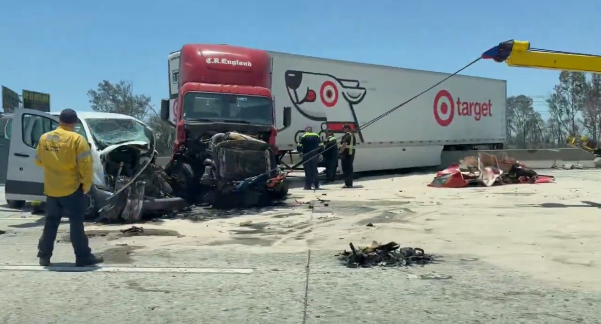 Emergency responders work at the scene of a serious truck accident involving a C.R. England truck and a damaged van on a highway.