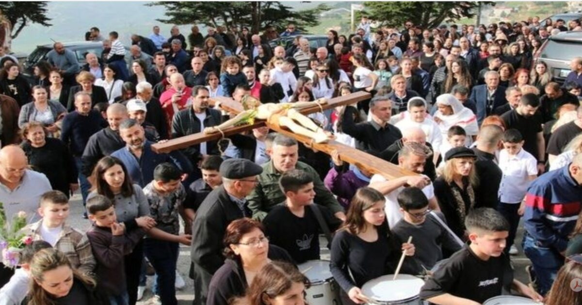Crowd participating in a religious procession, carrying a large wooden cross, showcasing a vibrant community gathering.